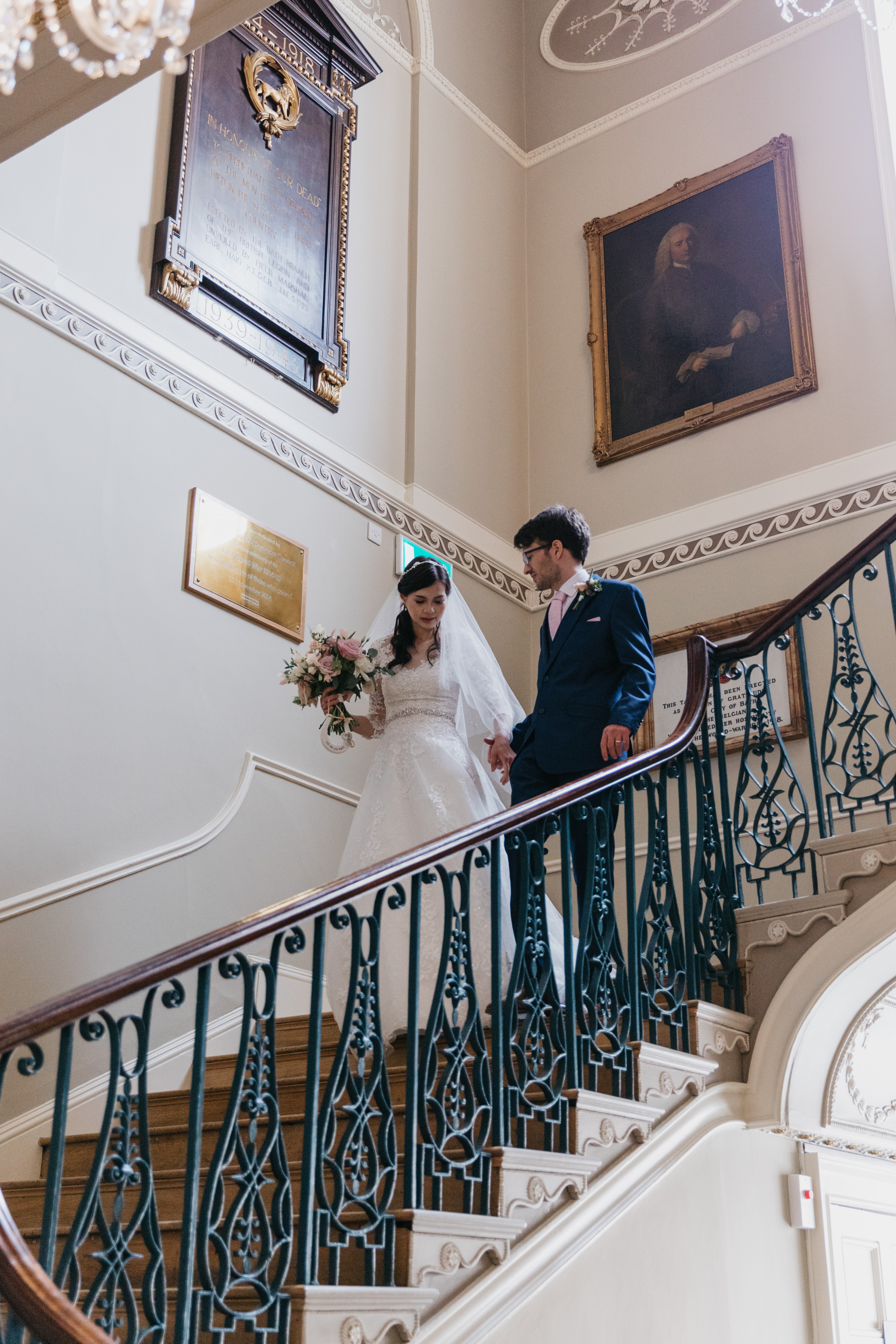 Wedding couple walk down the oak stairs at the Guildhall