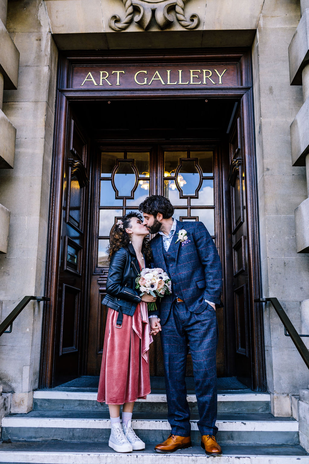 Bride and groom kiss on steps of Victoria Art Gallery