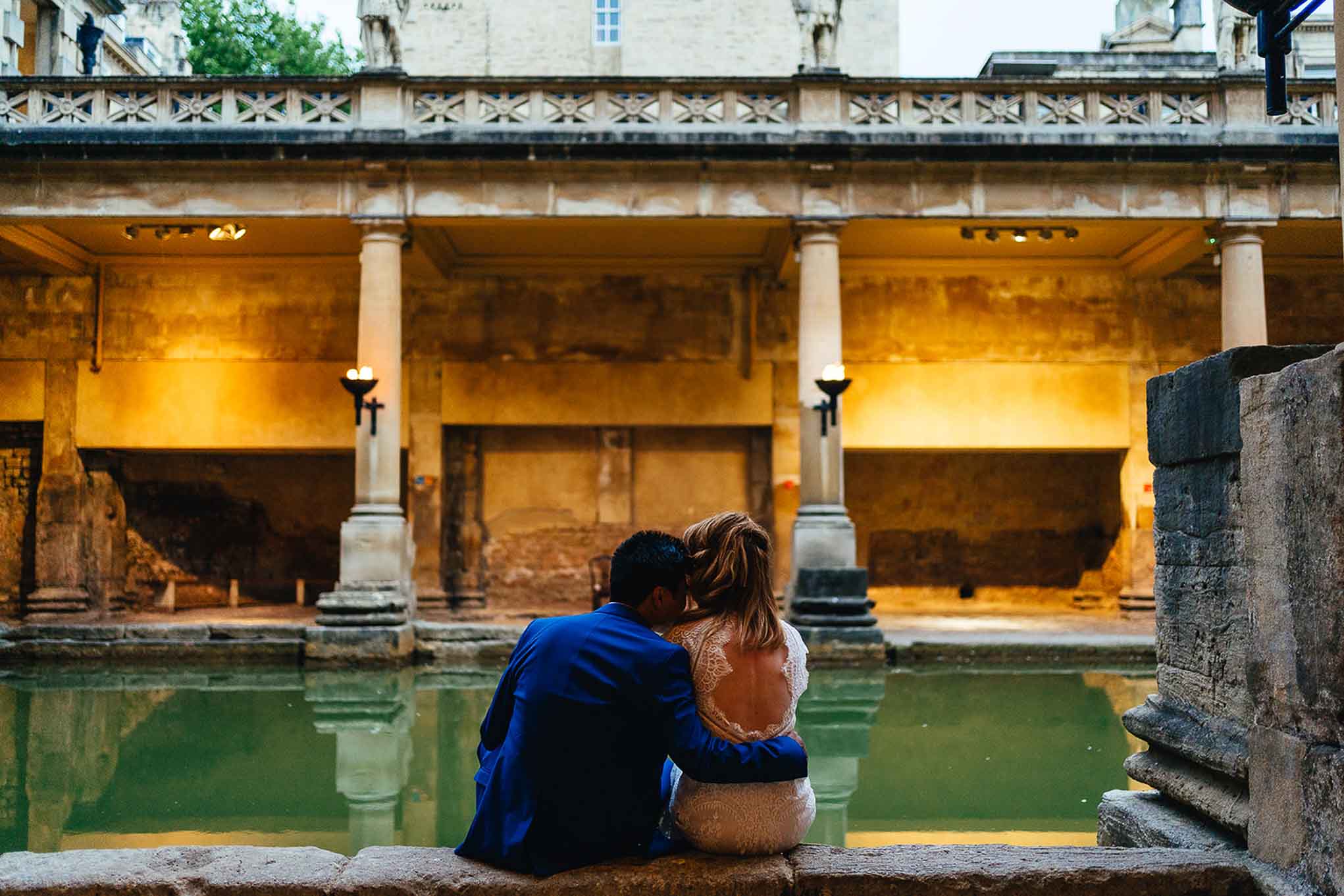 Couple seated on edge of the Great Bath embrace